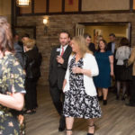 A group of men and women walking and talking in a hallway during the 2018 YCEA dinner
