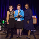 Three women are posing for a picture while holding an award during the 2018 YCEA dinner