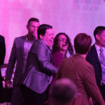 A group of men in suits and women in dresses laughing at the 2018 YCEA dinner
