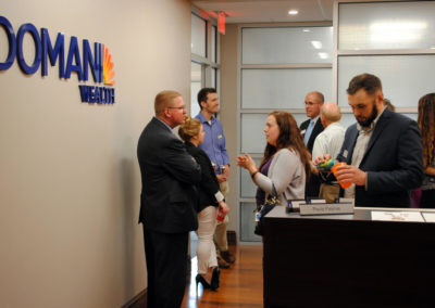 A group of people are standing in a room having conversations at Domani Wealth